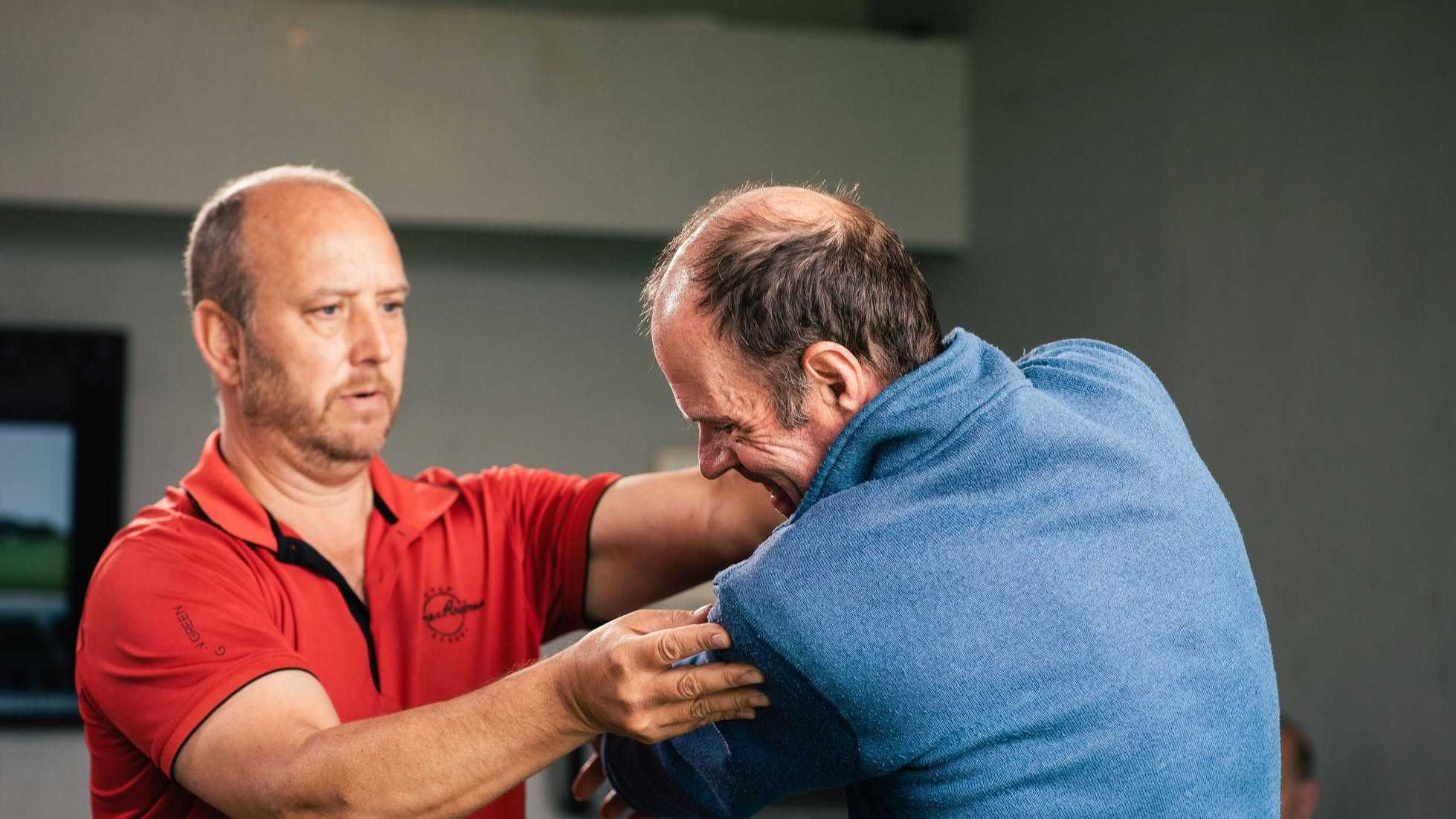A James Andrews Golf School coach adjusting a golfer's shoulder position during a lesson
